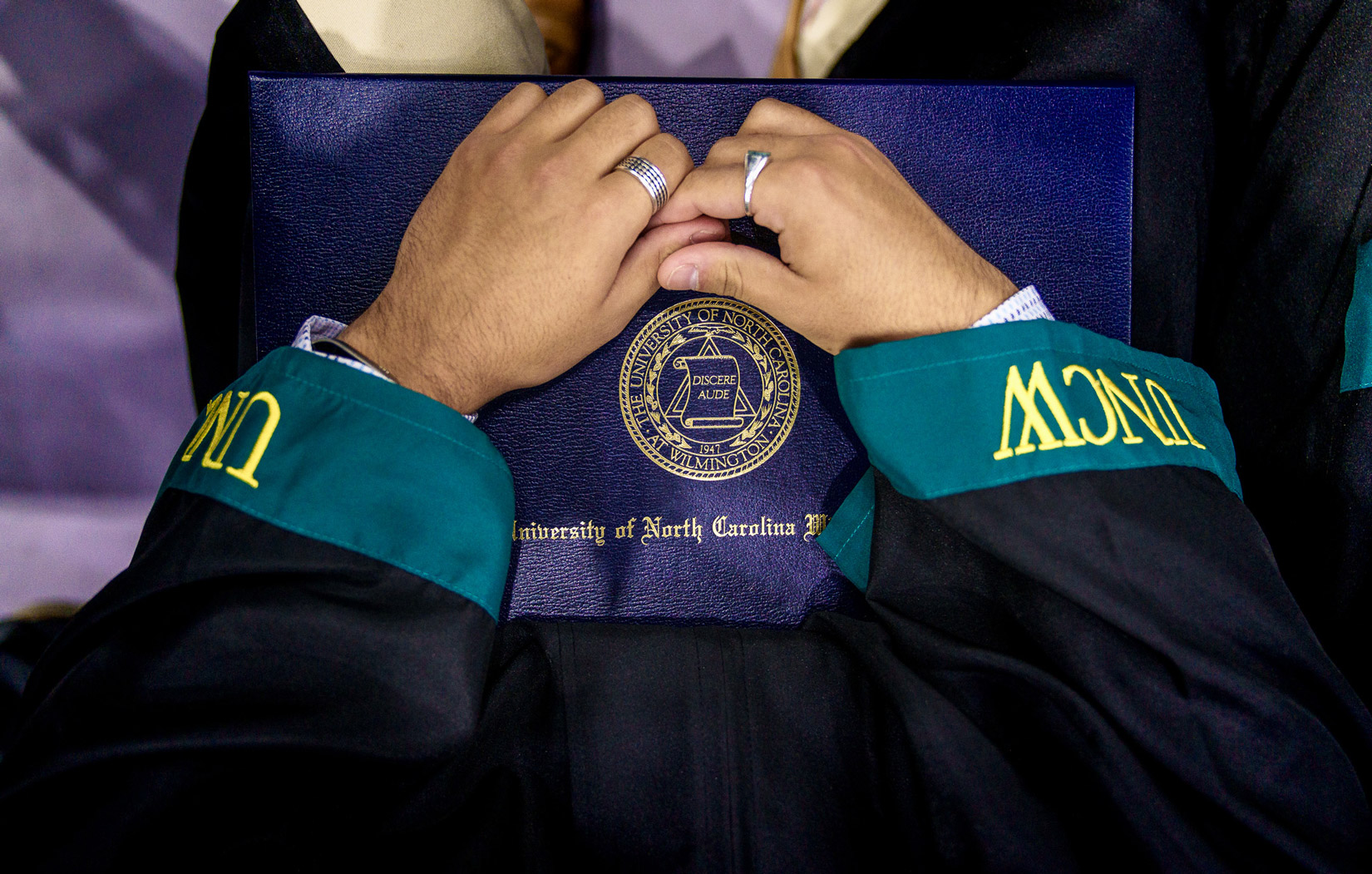 student holding commencement diploma in their regalia