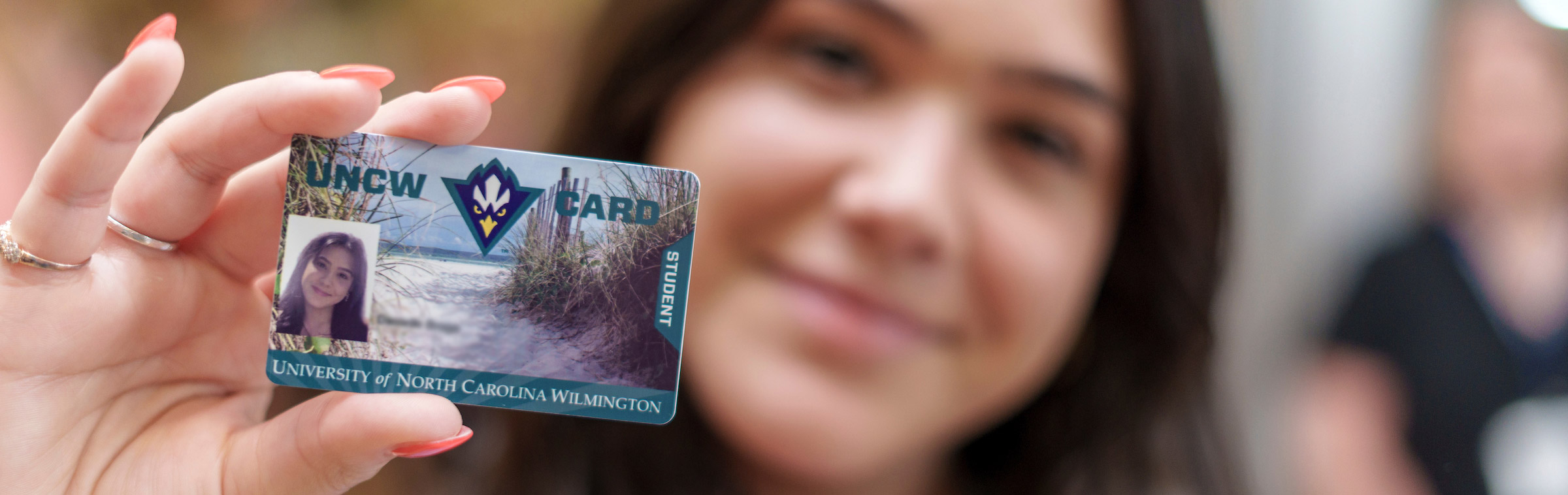student in the background showing a UNCW one card