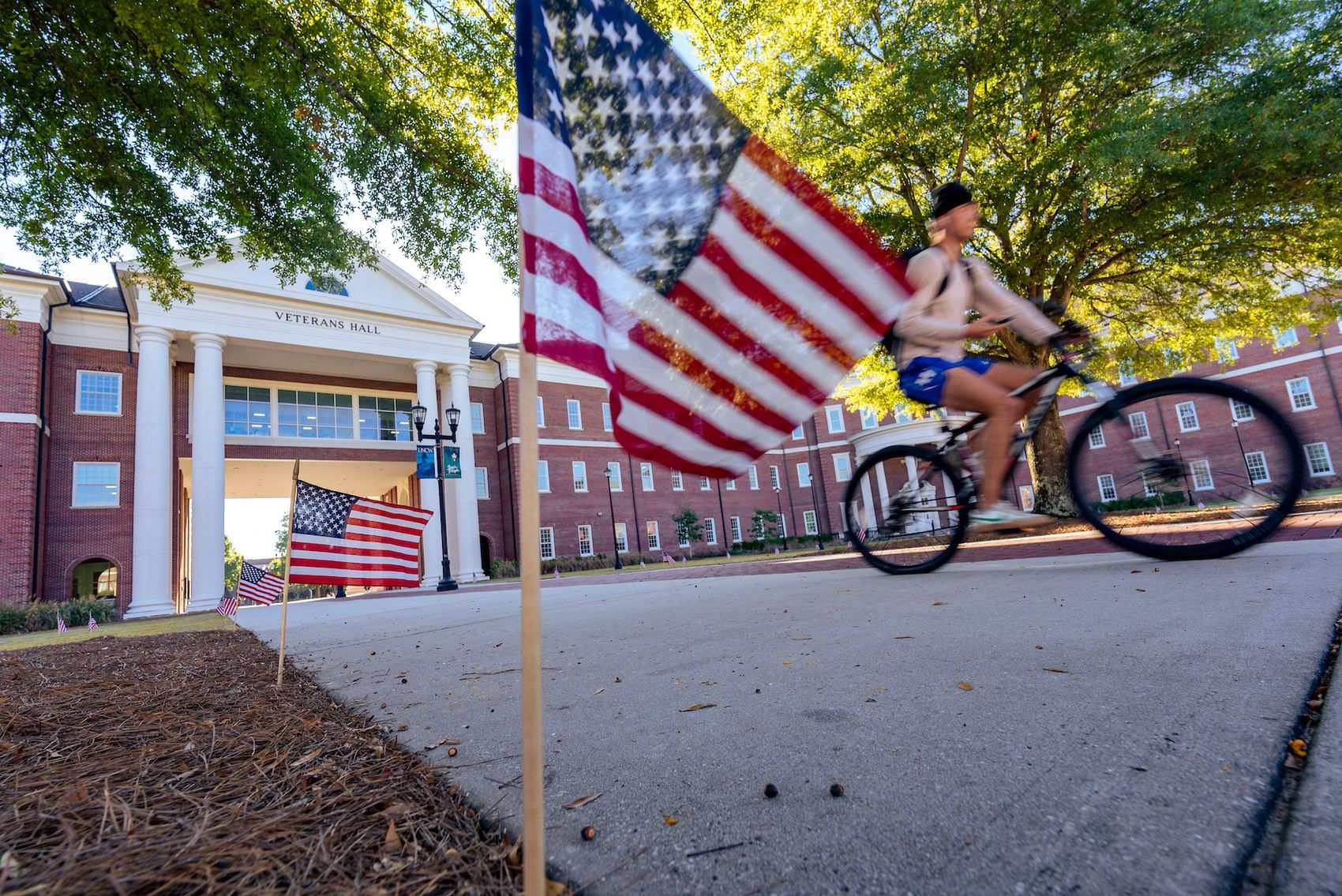 Bike rider glides down Chancellor's Walk in front of Veteran's Hall
