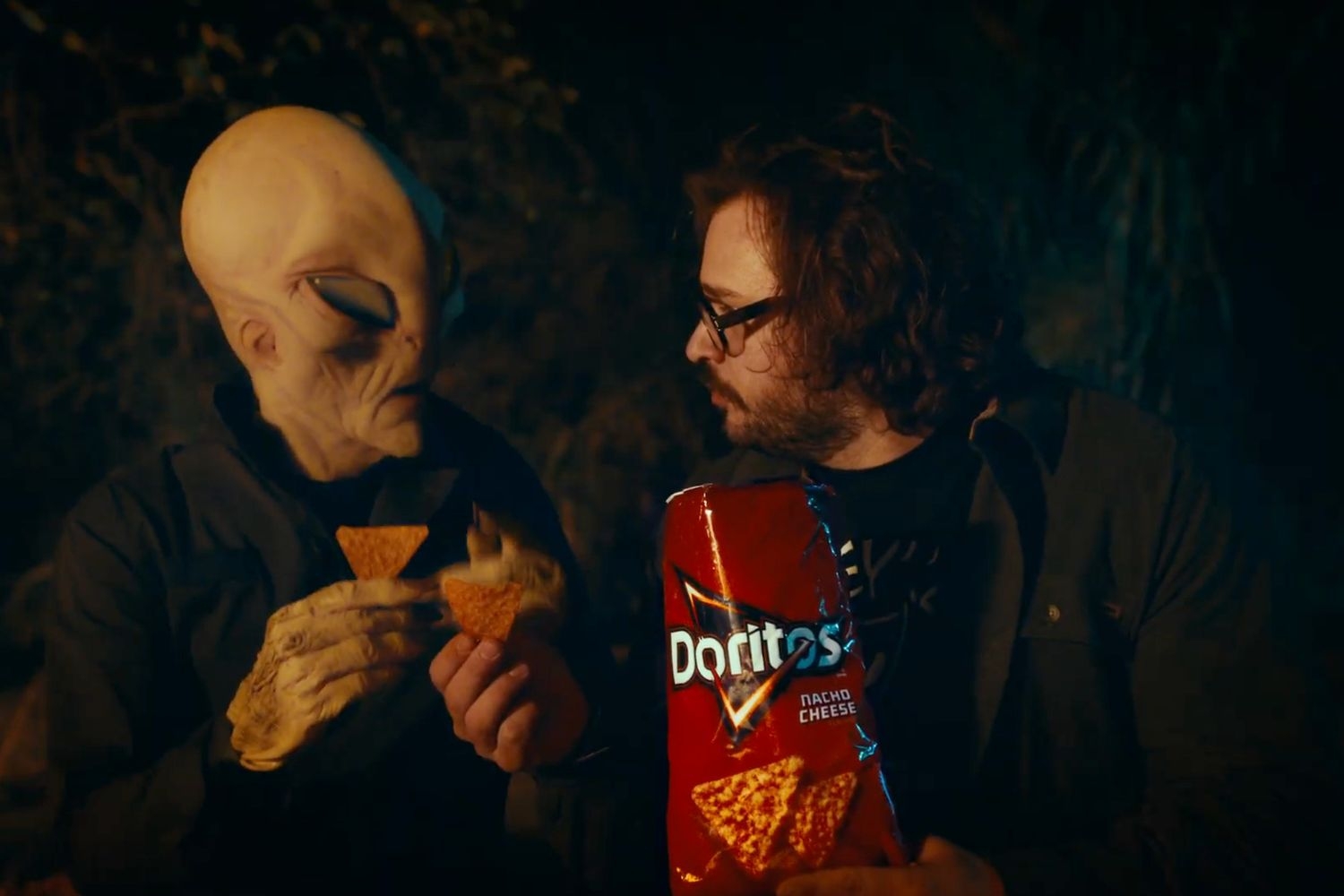 Man poses with alien and bag of Doritos