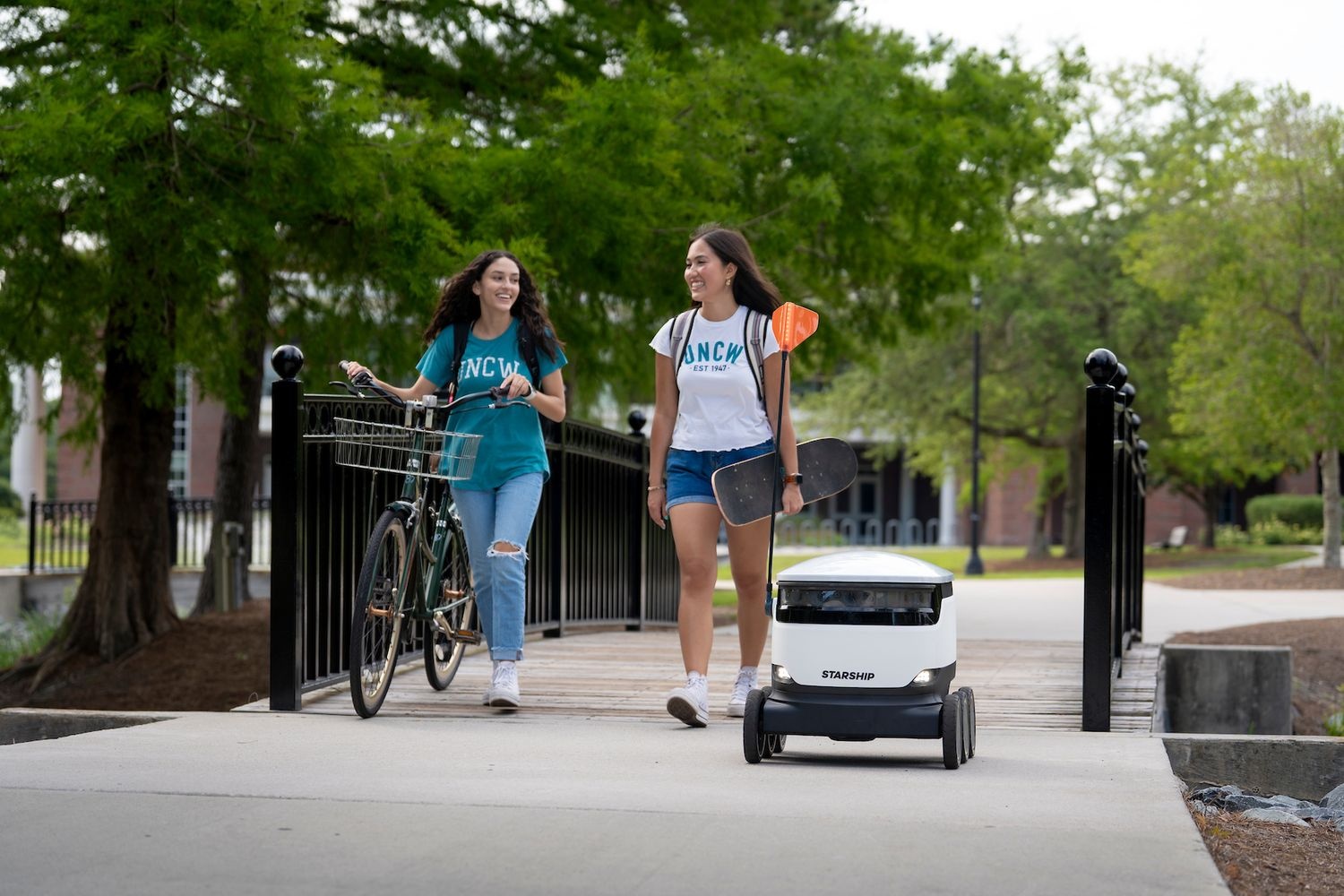 Two students walking alongside Starship robot