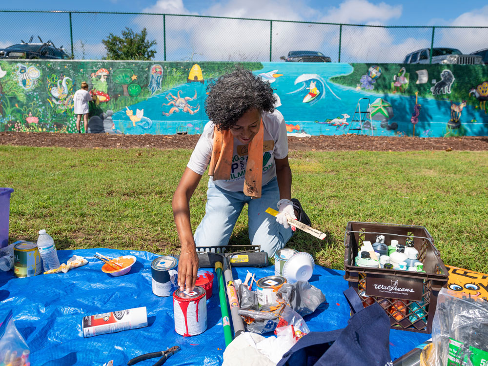 Volunteer paints a mural outside