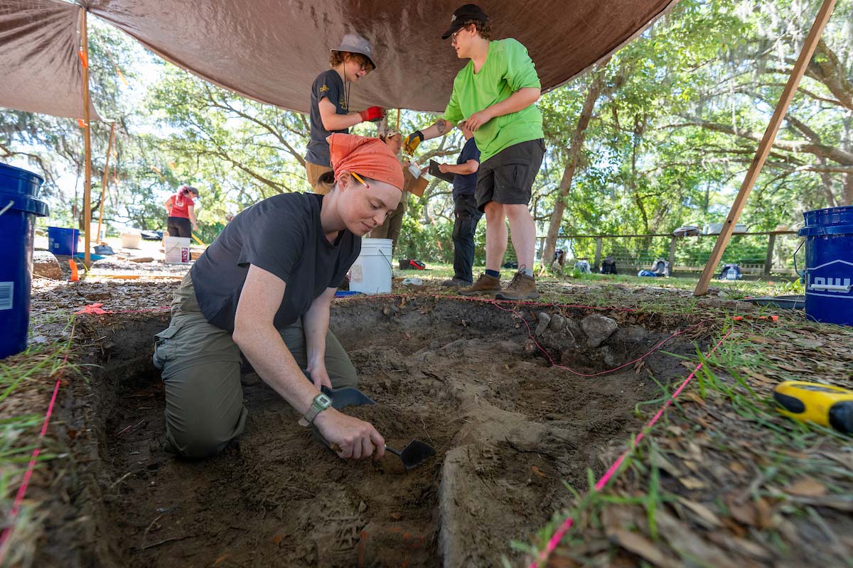 Students remove and sift dirt from a dig