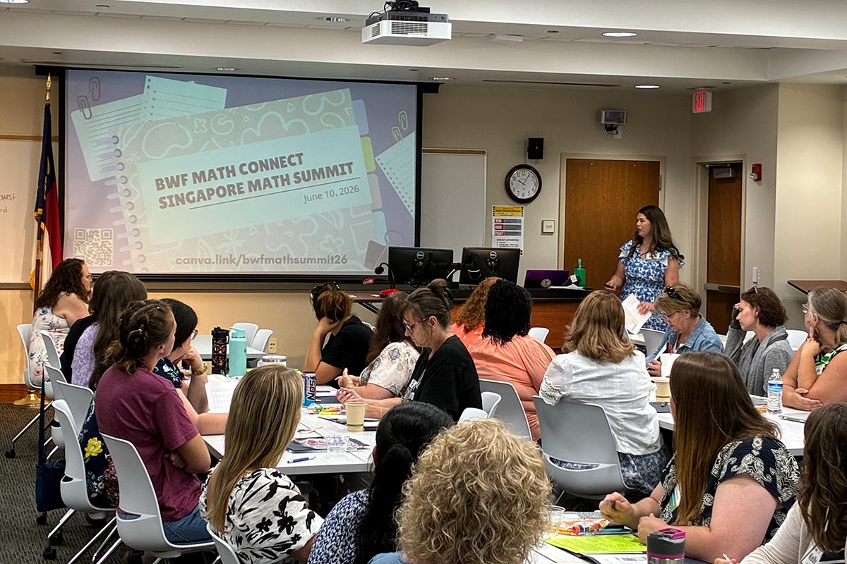 Educators sit at tables before a presentation screen