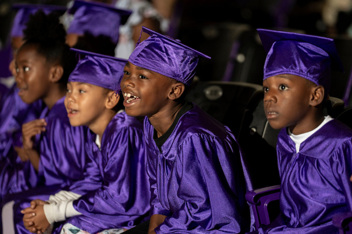 Young boys in caps and gowns laugh and smile