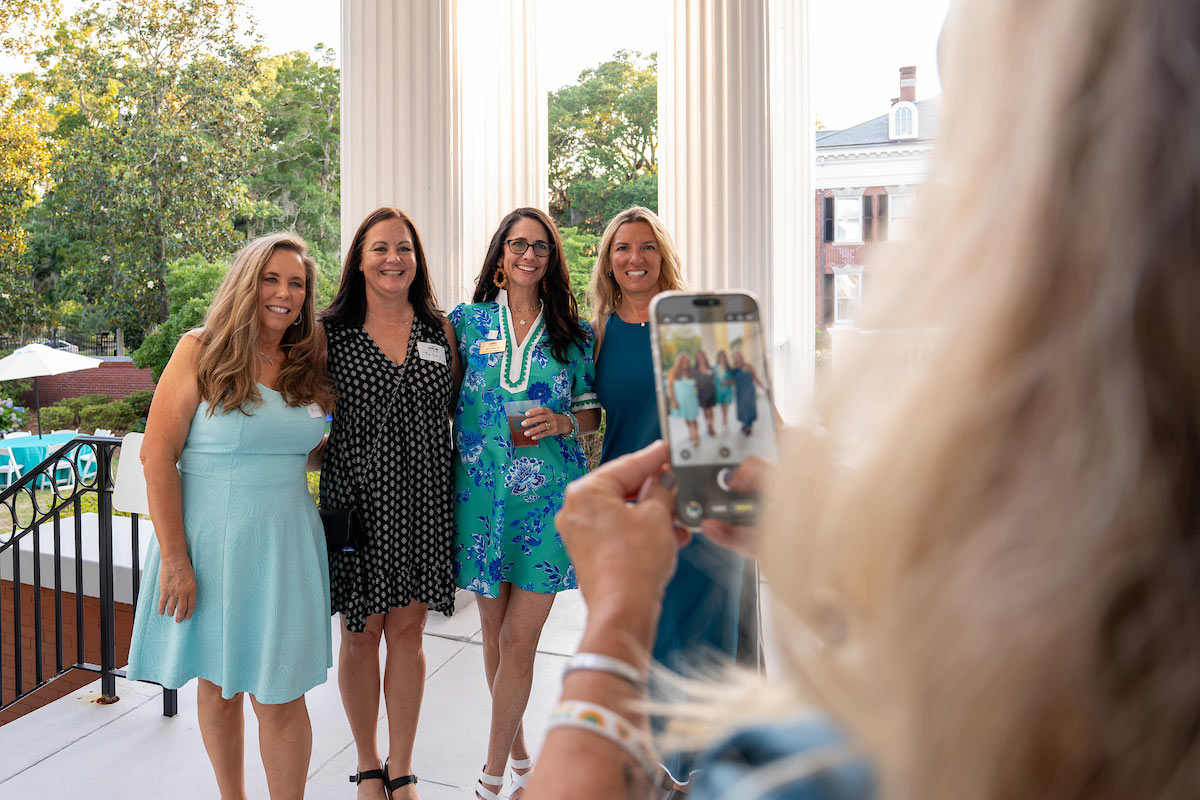 Four women pose for a cellphone photo at the historic Wise Alumni House