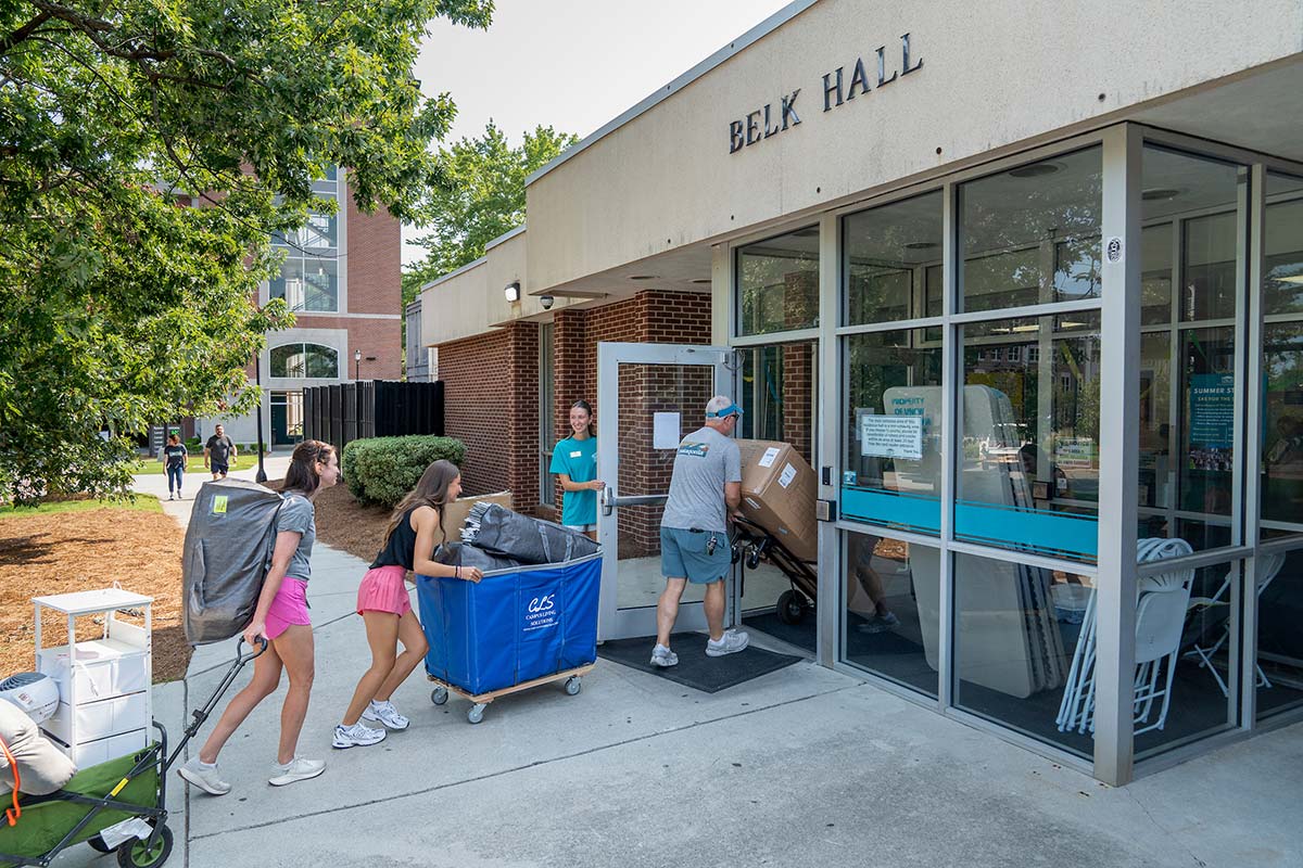 People push and drag carts and dollies into Belk Hall during Move-In