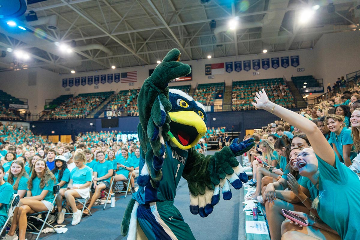 Sammy C. Hawk high-fives a student in Trask Coliseum