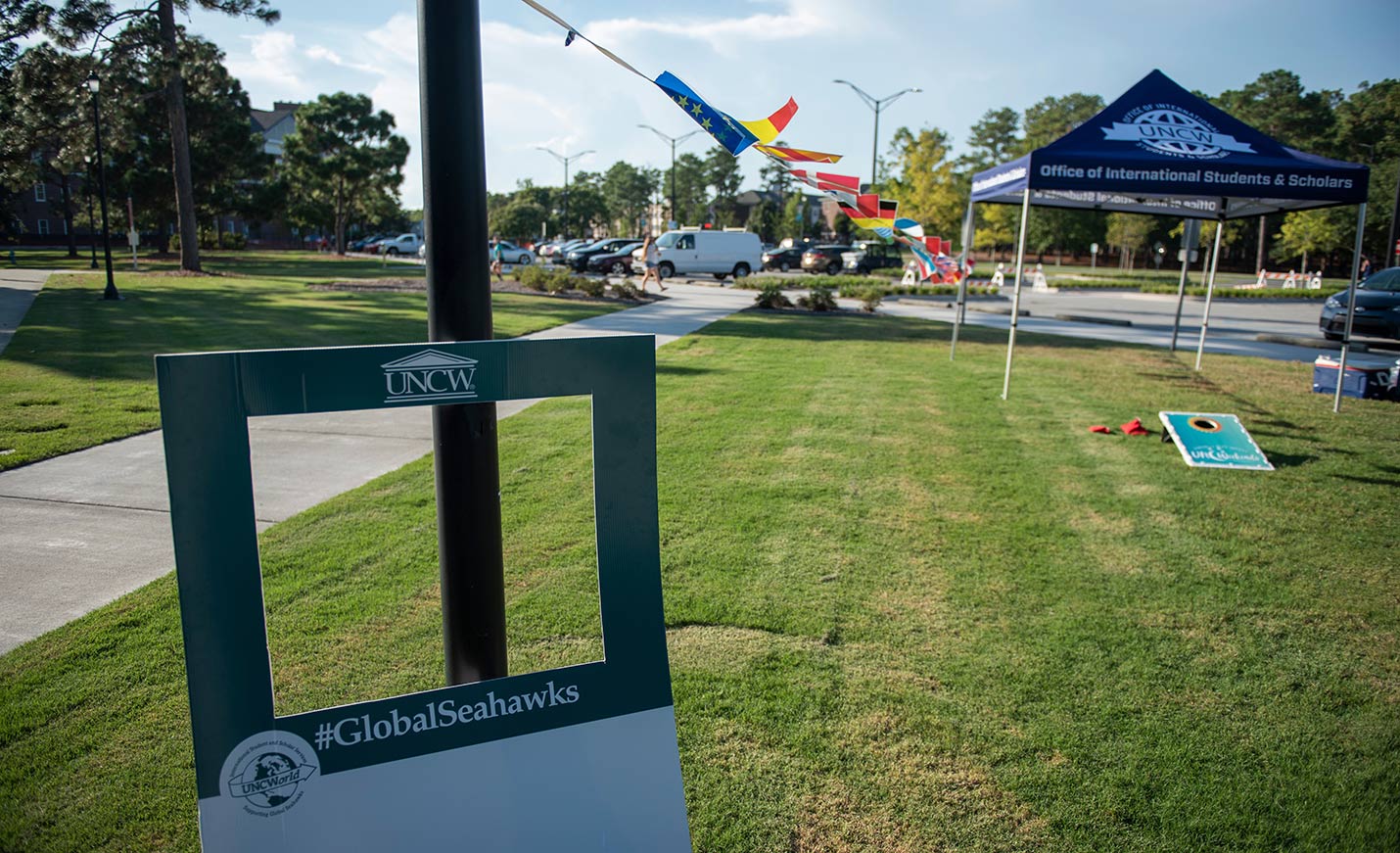 campus scene with international flags flying next to a tent for the Office of International Students