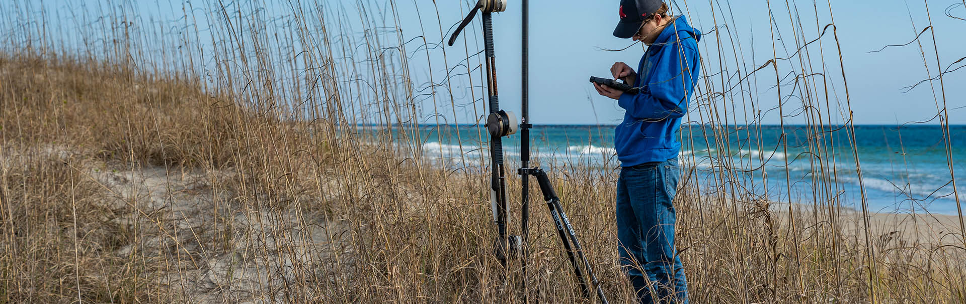 Man adjusting equipment near lake.