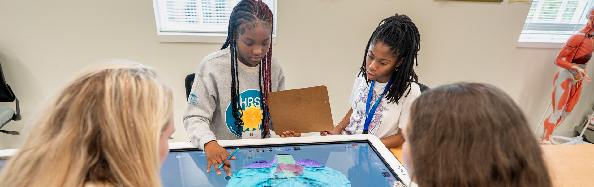 Rising high school students work a virtual desktop on an Anatomage Table showcasing a digitize human cadaver as part of iHPSS (Interdisciplinary Health Professions Summer Summit) summer camp