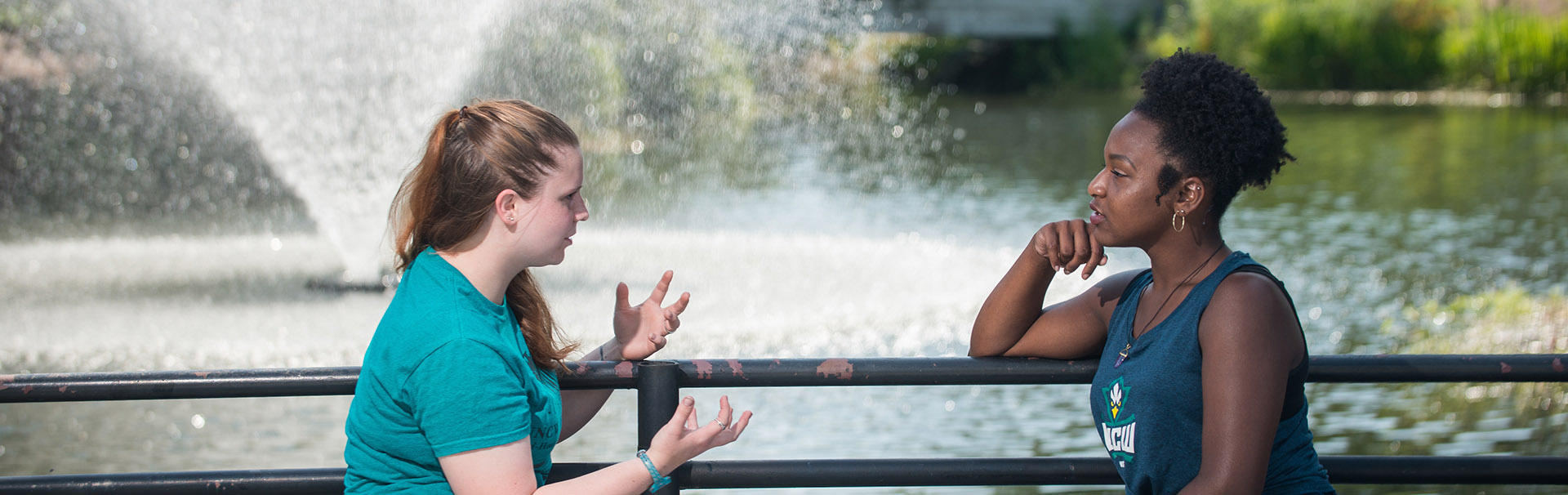 Two women talking in front of water fountain.