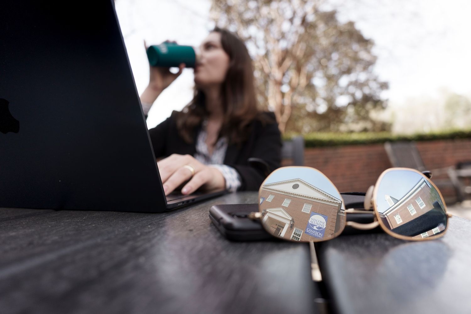 female on laptop with Cameron hall reflected in sunglasses