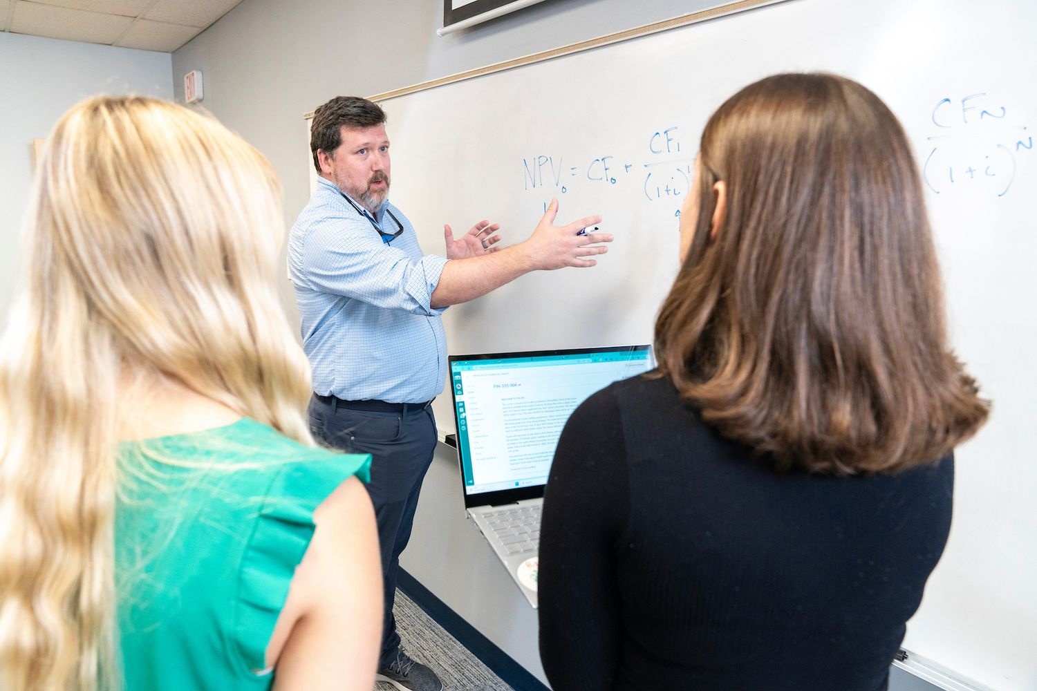 teacher with two students teaching on a whiteboard
