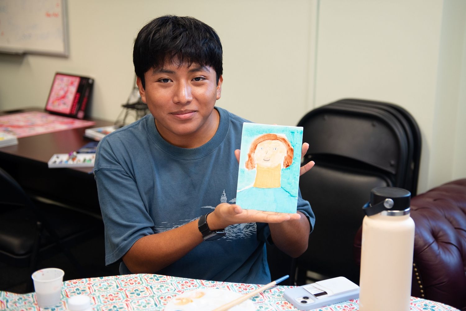 A student holds up a painting made during the Hispanic Cultural Fair