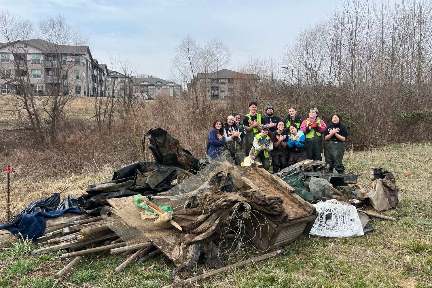 Students cleaning up debris in a field by campus
