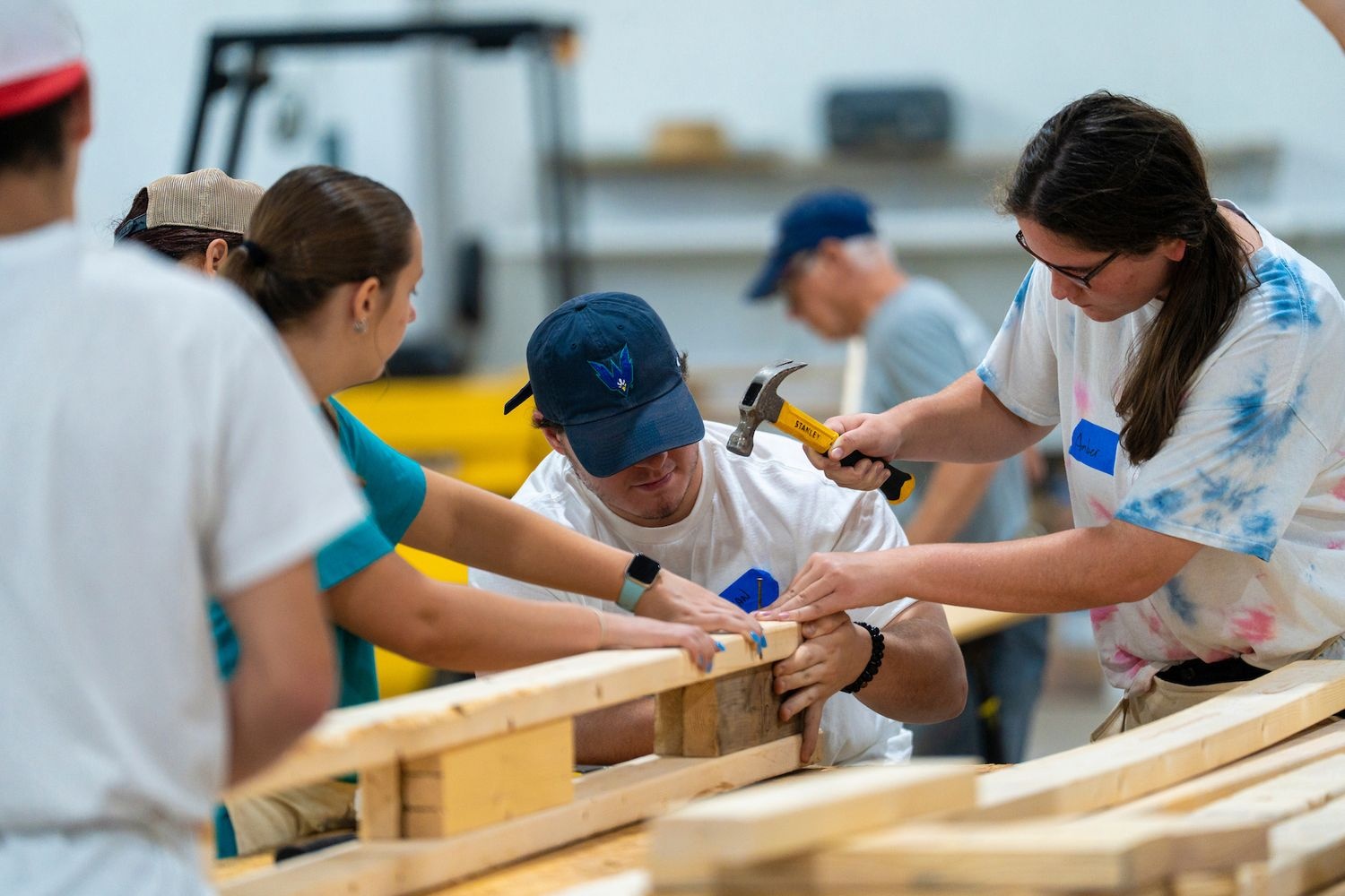 Three participants hammering nails into a piece of wood