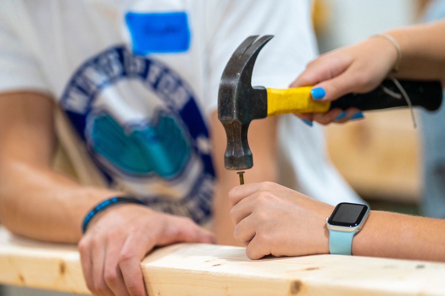 people hammering a nail into a piece of wood