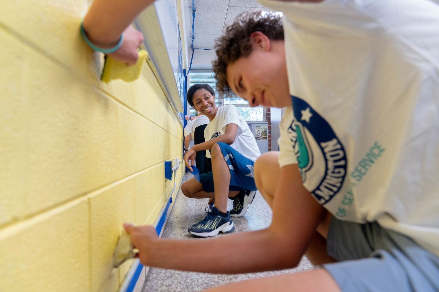 two wings up participants painting a wall yellow