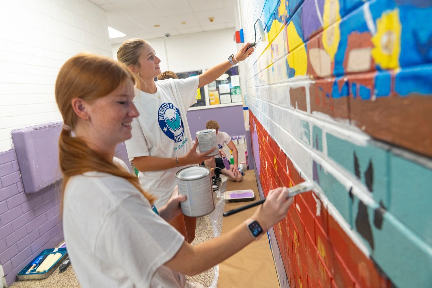 Wings up participants painting a wall