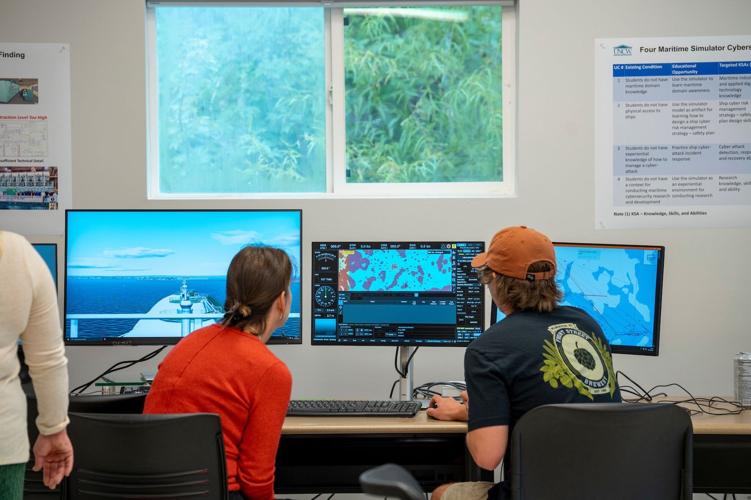Students use a maritime navigation simulator on multiple computer screens in a classroom.