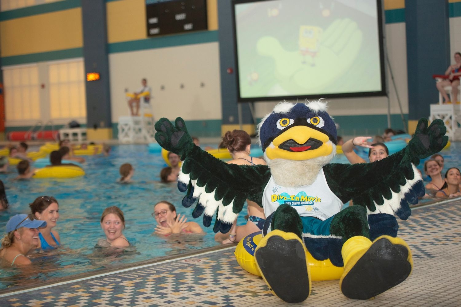 Students playing in pool with sammy seahawk on the pool ledge.