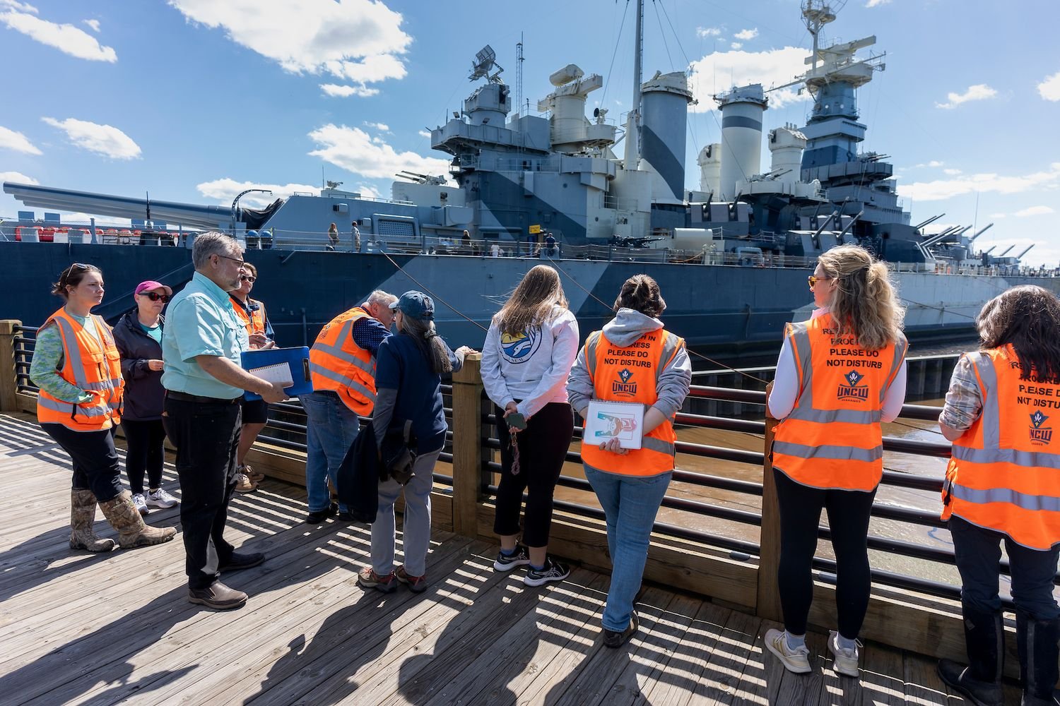 Class on the Riverwalk with Battleship in the background
