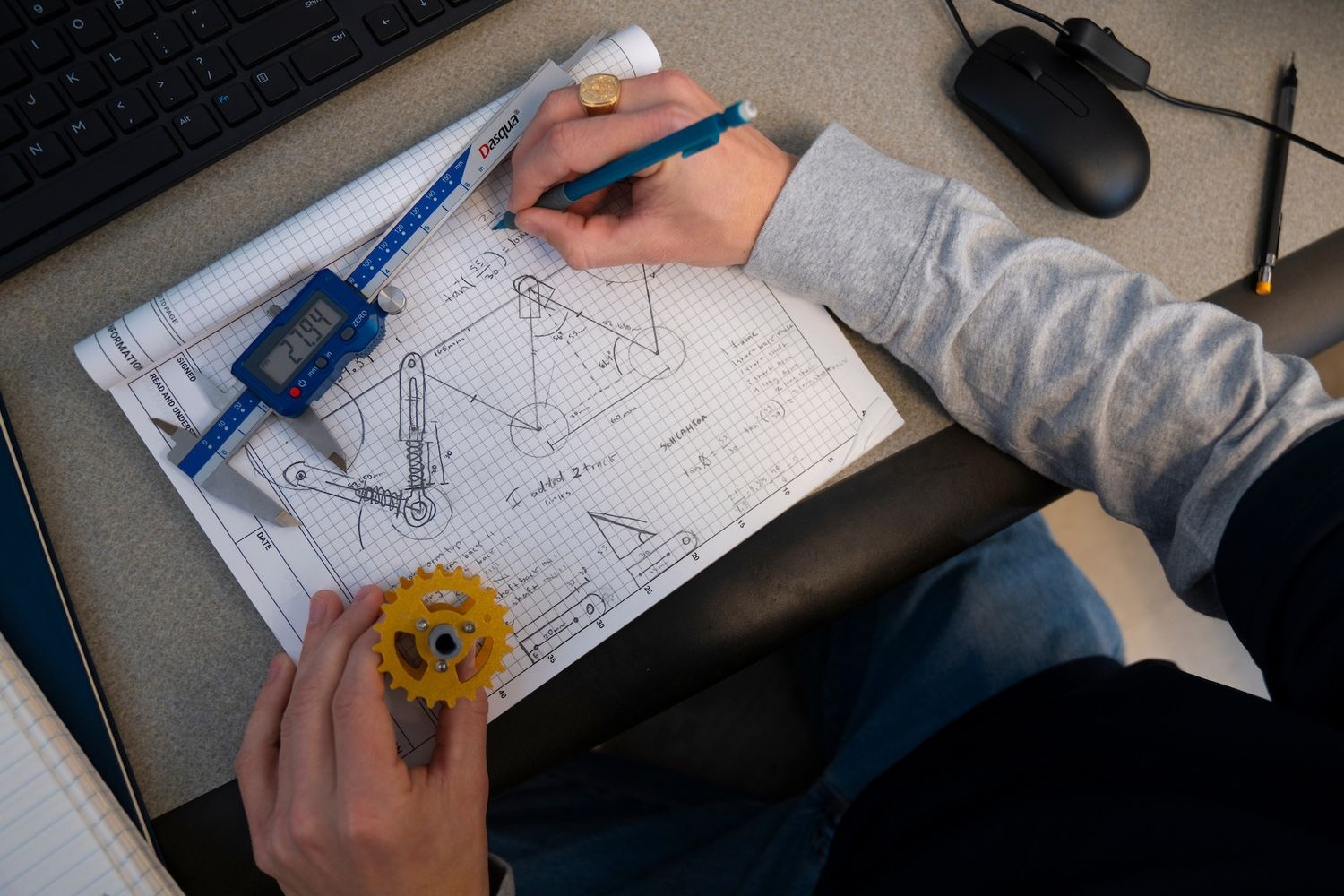 Student sketching parts and math equations for a farmbot
