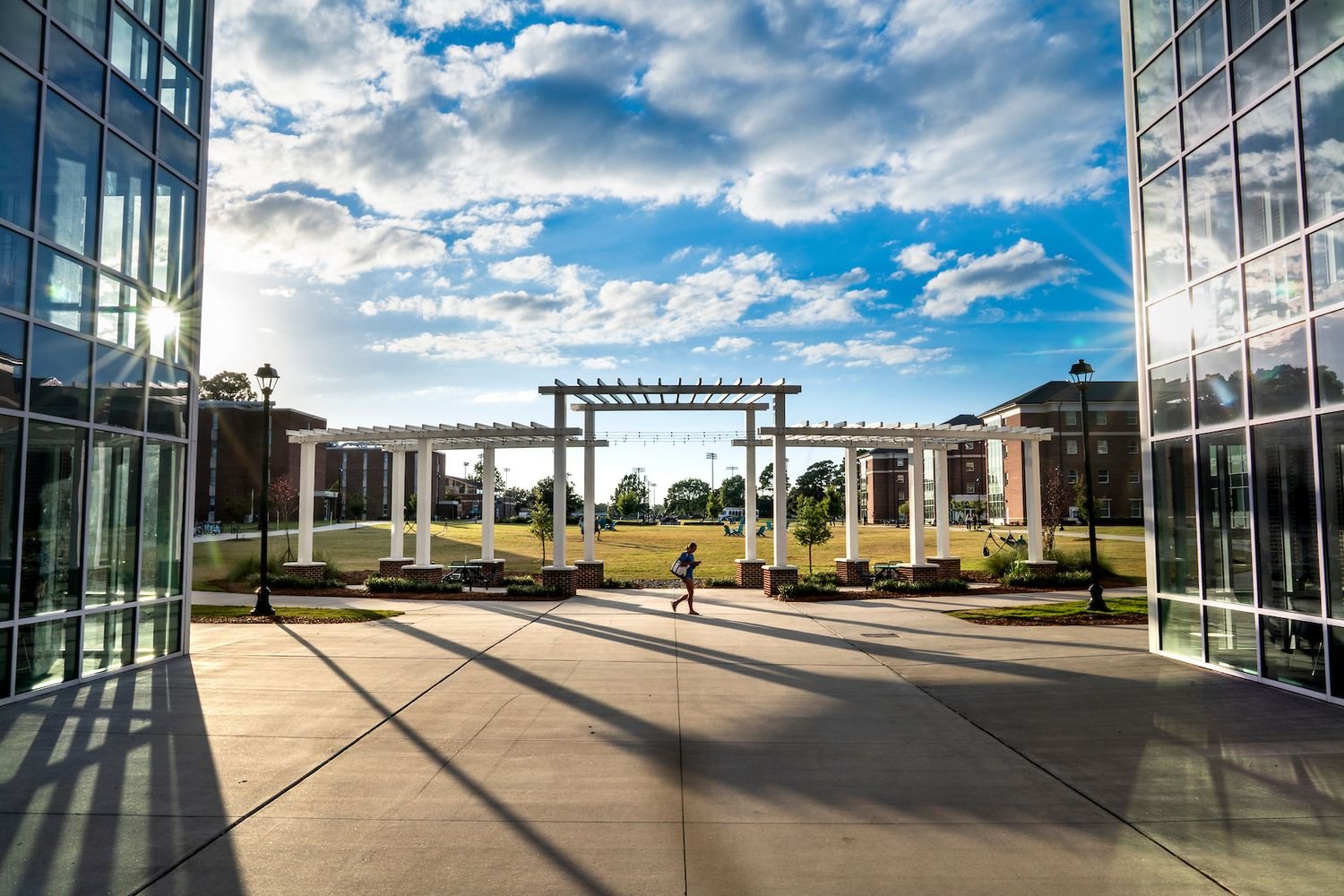 student walks as the sun cast shadows between Loggerhead and Terrapin Halls near the Seahawk Quad