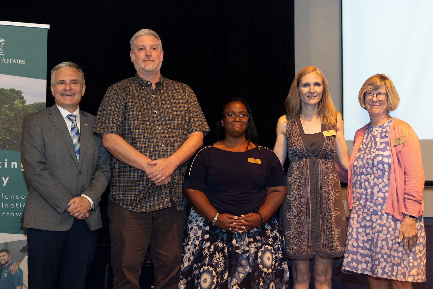 Five faculty members standing on stage for a celebration