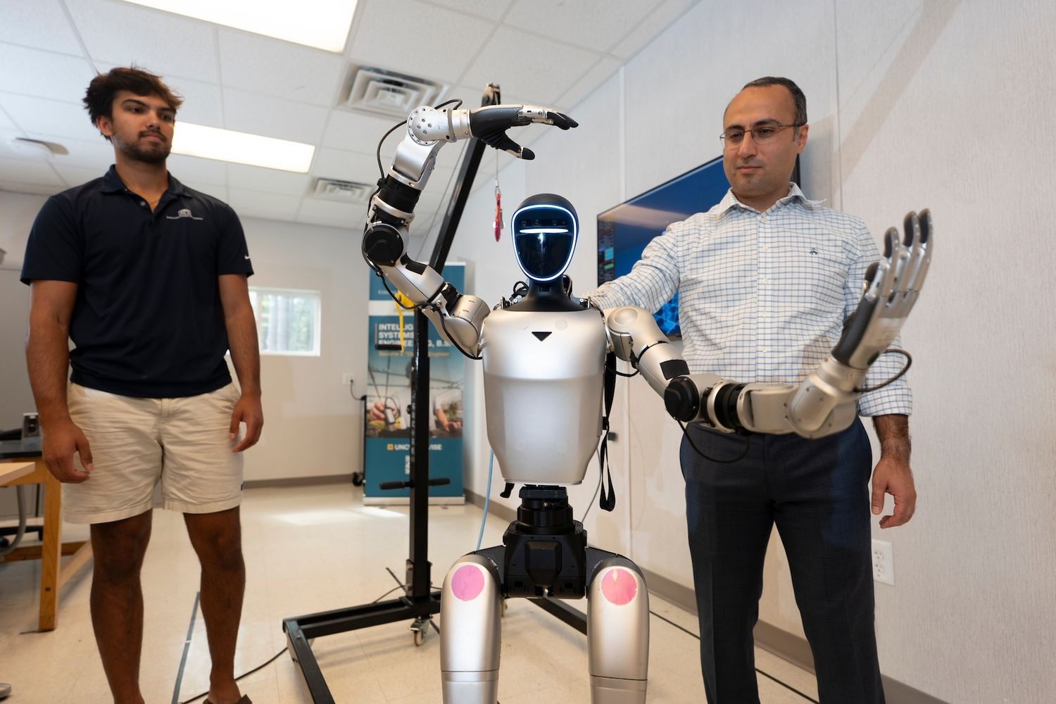 James Caddell and Hamed Saeidi working with UNCW's humanoid robot.  