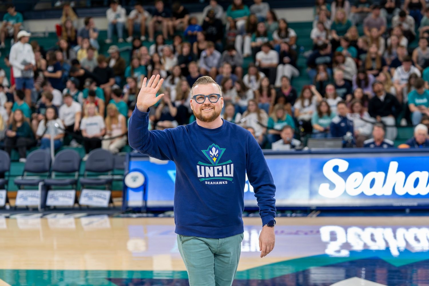 Trevor Todd ’16 2026 UNCW Distinguished Young Alumnus of the Year standing on court at Trask Coliseum 