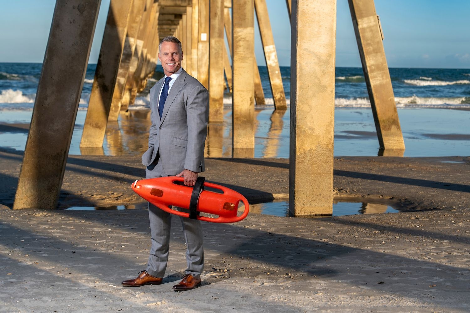 Sam Proffitt stands on the beach holding a rescue buoy