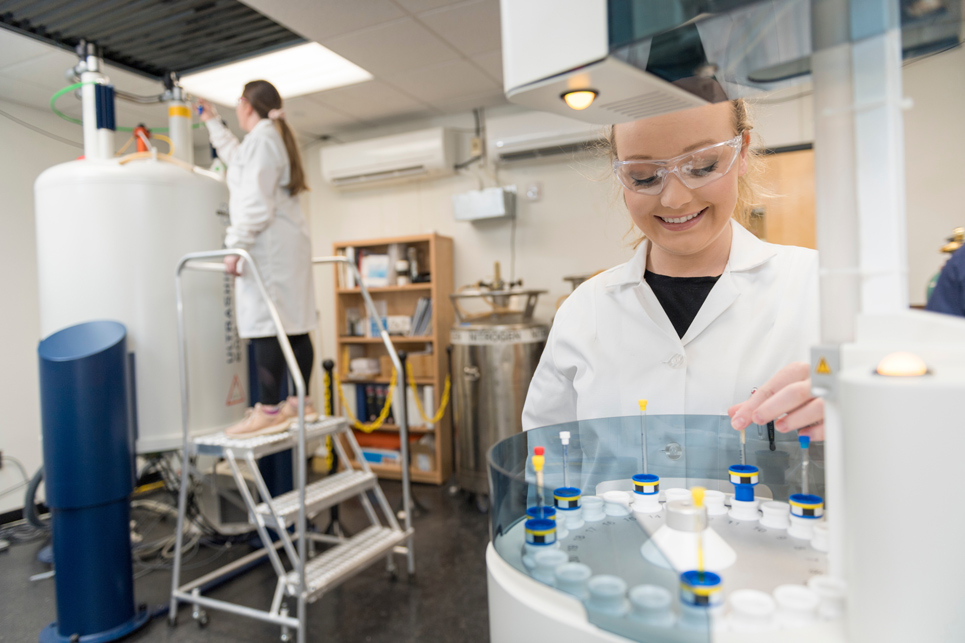 Alt: Two students working in a laboratory in white lab coats