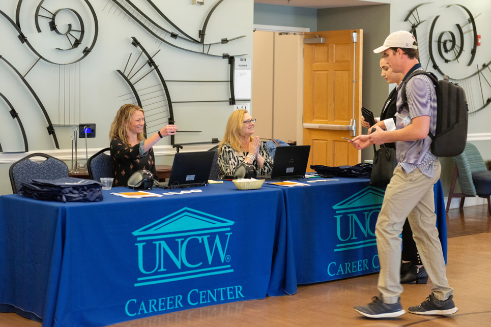 Two students approach a desk at a career center event